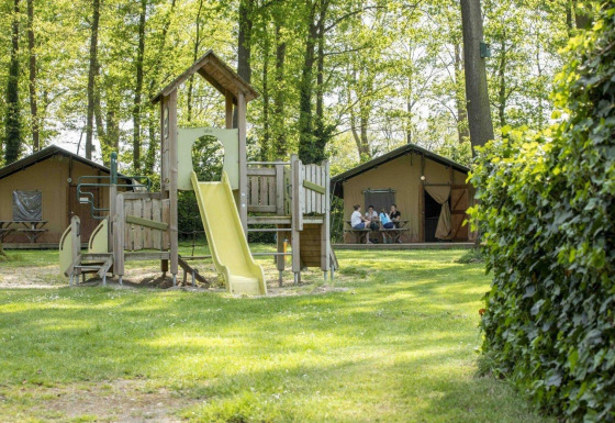 Parque infantil y tiendas safari en Recreation Park Den Blanken, Países Bajos, con familias en el fondo.
