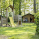 Legeplads og safaritelte i baggrunden på Rekreativ Park Den Blanken, Holland, omgivet af grønt og skov.
