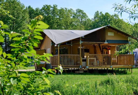 Tienda safari Ranger Lodge en Recreation Park Den Blanken, Países Bajos, rodeada de vegetación verde.