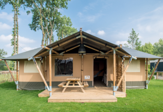 Safari tent Medley Lodge with covered porch, picnic table and lawn, perfect for outdoor relaxation.