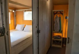 Interior view of Medley Lodge safari tent with double bed and open wardrobe at Den Blanken, Netherlands.