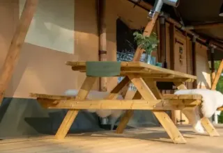 Mesa de picnic de madera junto a la tienda safari Medley Lodge con jacuzzi en Recreation Park Den Blanken, Países Bajos.