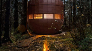 Aftenbillede af et rundt tiny house, The Nutshell, med bålplads i skoven ved Den Blanken, Holland.