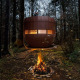 Aftenbillede af et rundt tiny house, The Nutshell, med bålplads i skoven ved Den Blanken, Holland.