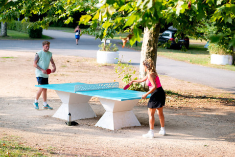 Due persone giocano a ping pong all'aperto sotto gli alberi al Camping de Thoissey, Auvergne-Rhône-Alpes, Francia.