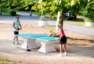 Due persone giocano a ping pong all'aperto sotto gli alberi al Camping de Thoissey, Auvergne-Rhône-Alpes, Francia.
