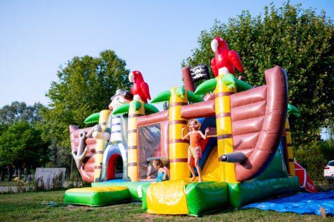 Enfants jouant sur un château gonflable en forme de bateau pirate au Camping de Thoissey en Auvergne-Rhône-Alpes.