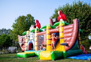 Enfants jouant sur un château gonflable en forme de bateau pirate au Camping de Thoissey en Auvergne-Rhône-Alpes.