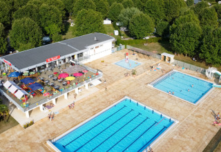 Luchtfoto van Camping de Thoissey met zwembaden, waterglijbaan, terras en groene bomen eromheen.