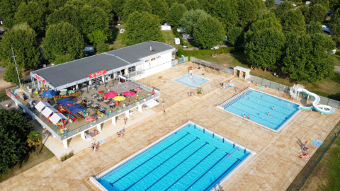 Vue aérienne du Camping de Thoissey avec piscines, toboggan, terrasse ensoleillée et arbres verts.