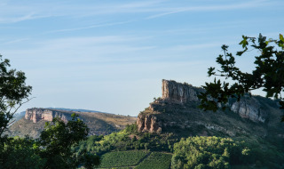 Bjergrigt landskab nær Thoissey, Auvergne-Rhône-Alpes, Frankrig, med klippeformationer og grønne træer.