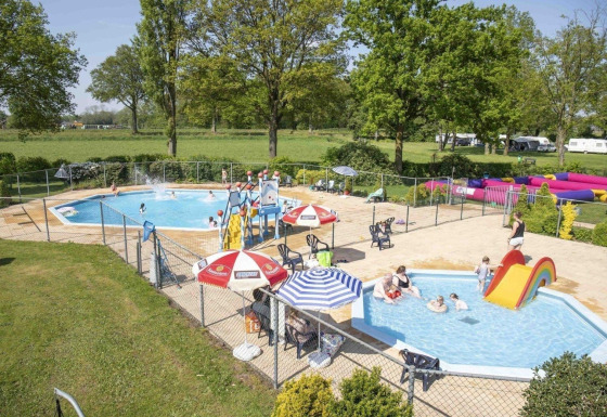 Børnevenligt udendørs poolområde i Rekreationspark Den Blanken med rutsjebane og afslappende stemning.