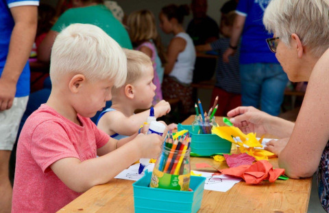 Niños y un adulto haciendo manualidades juntos en una mesa en el parque de vacaciones Den Blanken, Gelderland.
