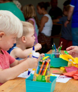 Niños y un adulto haciendo manualidades juntos en una mesa en el parque de vacaciones Den Blanken, Gelderland.
