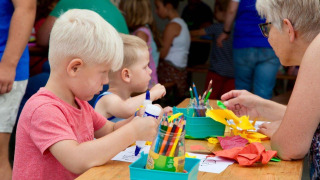Niños y un adulto haciendo manualidades juntos en una mesa en el parque de vacaciones Den Blanken, Gelderland.