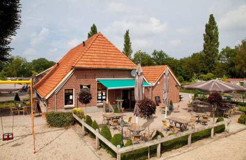 Zona de terraza exterior en el Recreation Park Den Blanken en Gelderland, Países Bajos, con mesas y sombrillas.