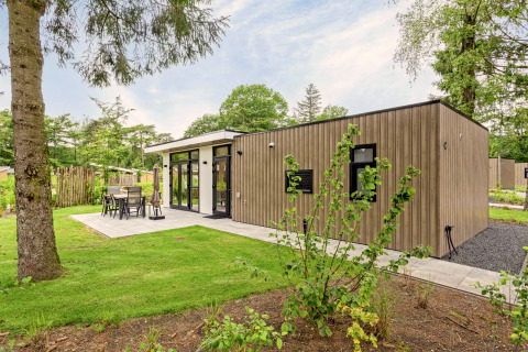 Moderne lodge, Module Special Wellness, met houten gevel, terras en groene, bosrijke omgeving.