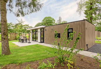 Moderne lodge, Module Special Wellness, met houten gevel, terras en groene, bosrijke omgeving.