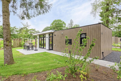 Moderne lodge, Module Special Wellness, met houten gevel, terras en groene, bosrijke omgeving.