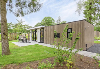 Modern lodge called Module Special Wellness with wood exterior, patio area, and lush green surroundings.