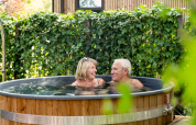 Pareja mayor relajándose en jacuzzi al aire libre en Module Special Wellness, Bospark Ede, Países Bajos.
