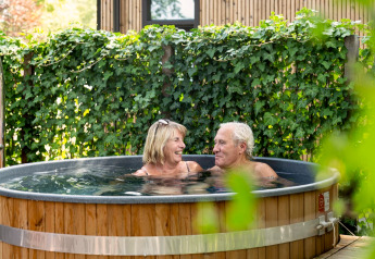 Pareja mayor relajándose en jacuzzi al aire libre en Module Special Wellness, Bospark Ede, Países Bajos.