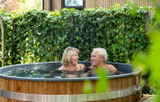 Ouder stel geniet in een hottub bij Module Special Wellness in Bospark Ede, omgeven door groen.