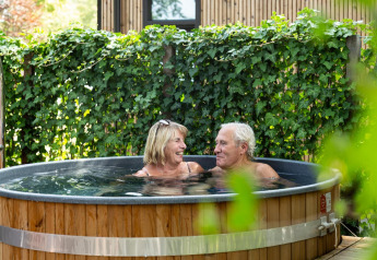 Pareja mayor relajándose en jacuzzi al aire libre en Module Special Wellness, Bospark Ede, Países Bajos.