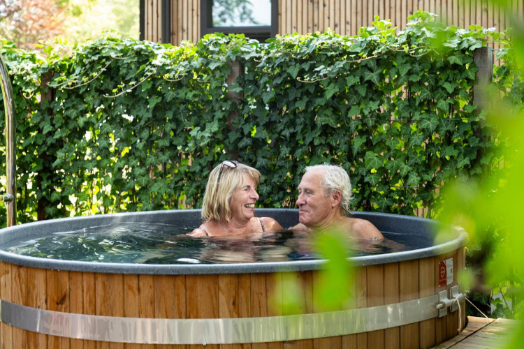 Pareja mayor relajándose en jacuzzi al aire libre en Module Special Wellness, Bospark Ede, Países Bajos.