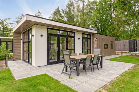 Moderne lodge met ruim terras en eettafel bij Bospark Ede, omgeven door groen, in Nederland.