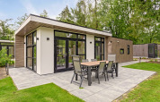 Lodge moderno con amplia terraza y comedor exterior en Bospark Ede, rodeado de naturaleza en los Países Bajos.