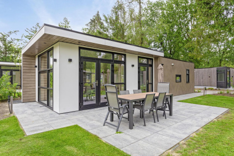 Lodge moderne avec grande terrasse et table à manger extérieure au Bospark Ede, entourée de verdure, Pays-Bas.