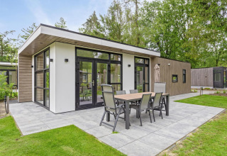 Lodge moderne avec grande terrasse et table à manger extérieure au Bospark Ede, entourée de verdure, Pays-Bas.