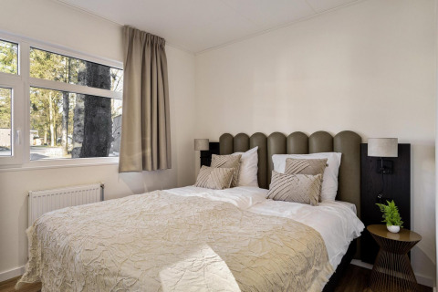 Dormitorio acogedor con cama doble, ventanales grandes y decoración moderna en la lodge Module Special Wellness.