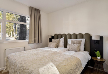 Gemütliches Schlafzimmer mit Doppelbett, großen Fenstern und moderner Einrichtung in der Lodge Bospark Ede.