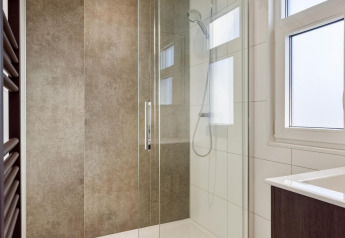 Douche moderne avec porte en verre et pommeau pluie dans une salle de bain de lodge à Bospark Ede, Pays-Bas.