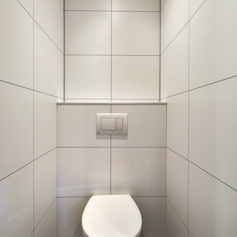 Minimalistische badkamer met witte tegels en wandcloset in Module Special Wellness, Bospark Ede, Nederland.