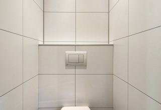 Minimalistische badkamer met witte tegels en wandcloset in Module Special Wellness, Bospark Ede, Nederland.