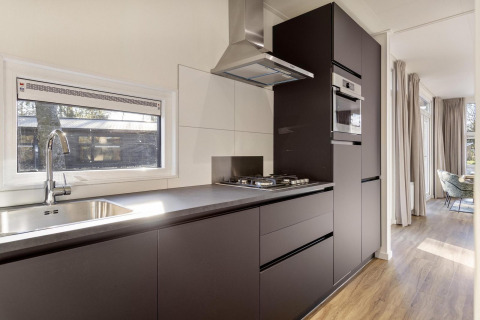 Moderne køkkenfaciliteter i lodge Module Special Wellness med sort indretning i Bospark Ede, Nederlandene.