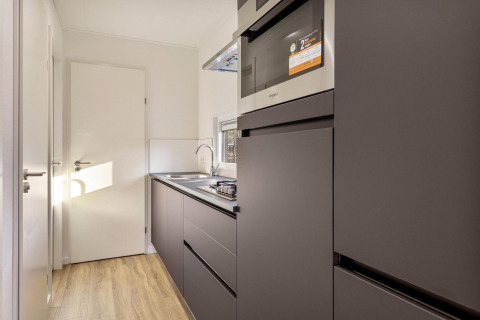 Moderne køkkenindretning i Module Special Wellness-lodge med mørke skabe og tidssvarende apparater.