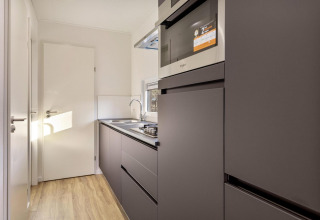 Moderne Küchenzeile in der Module Special Wellness-Lodge, Bospark Ede, mit dunklen Schränken und Geräten.