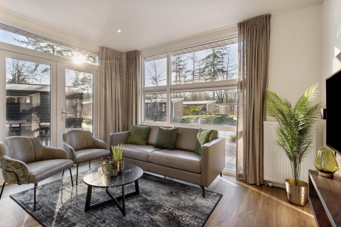 Modern lodge living room at Module Special Wellness, Bospark Ede, Netherlands, with large windows and chic décor.