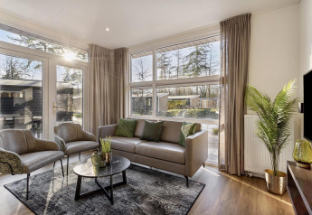 Modern lodge living room at Module Special Wellness, Bospark Ede, Netherlands, with large windows and chic décor.