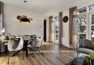 Moderne eet- en zithoek met grote ramen in een lodge op Bospark Ede, Nederland, stijlvol ingericht.