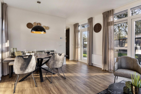 Salle à manger moderne avec salon et grandes fenêtres dans un lodge à Bospark Ede, Pays-Bas, décoration élégante.