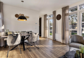 Moderne spise- og opholdsstue med store vinduer i en lodge på Bospark Ede, Holland, med stilfuldt interiør.