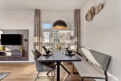 Moderne eethoek met stijlvolle stoelen en bank in de Module Special Wellness lodge op Bospark Ede, Nederland.