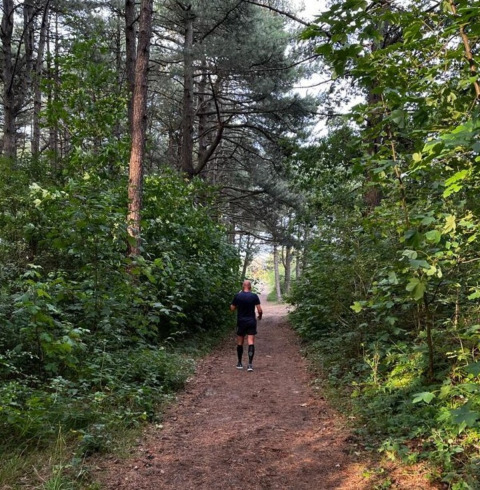 Une personne marche sur un sentier forestier au Camping Le Roptai, site majeur à Namur, Belgique.