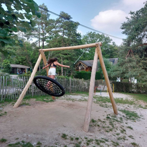 Ragazza che si dondola su un’altalena a rete in un parco giochi al Camping Le Roptai, Namur, Belgio.