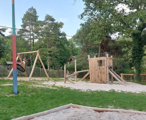 Parque infantil con columpios y torre de madera en Camping Le Roptai, un parque vacacional en Namur, Bélgica.